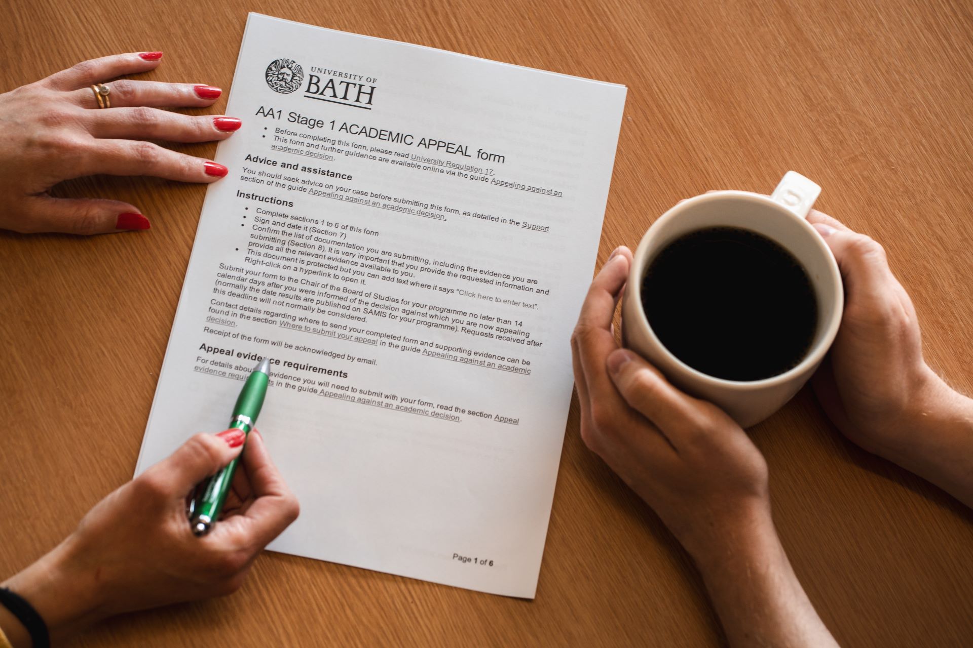 Advisor holds a pen on the academic appeal form, while student looks at form with a cup of coffee