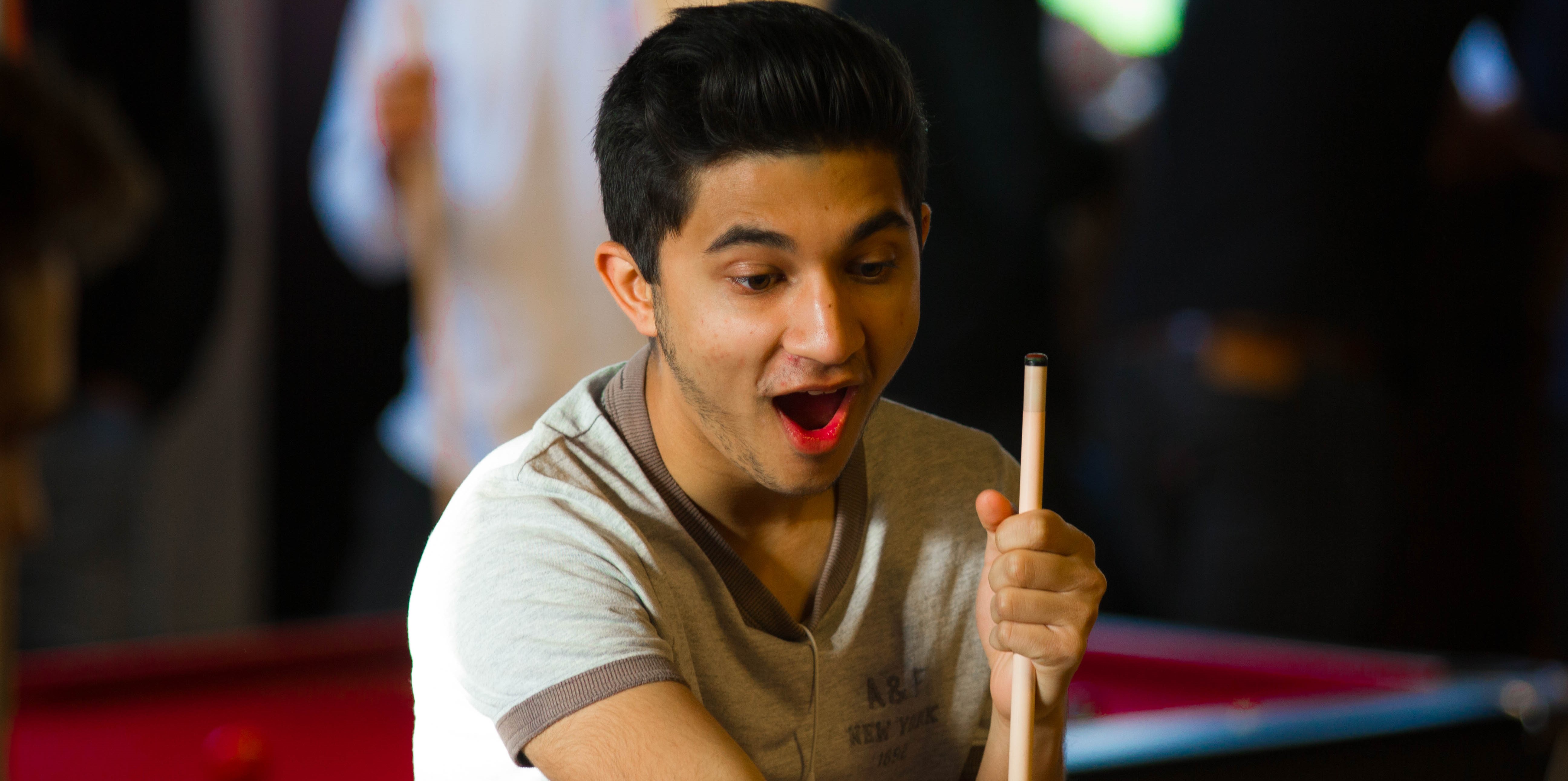 Student Pointing and smiling whilst playing pool