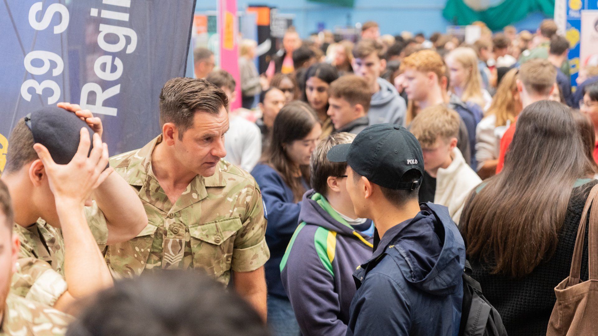 Student talking to army man in crowd