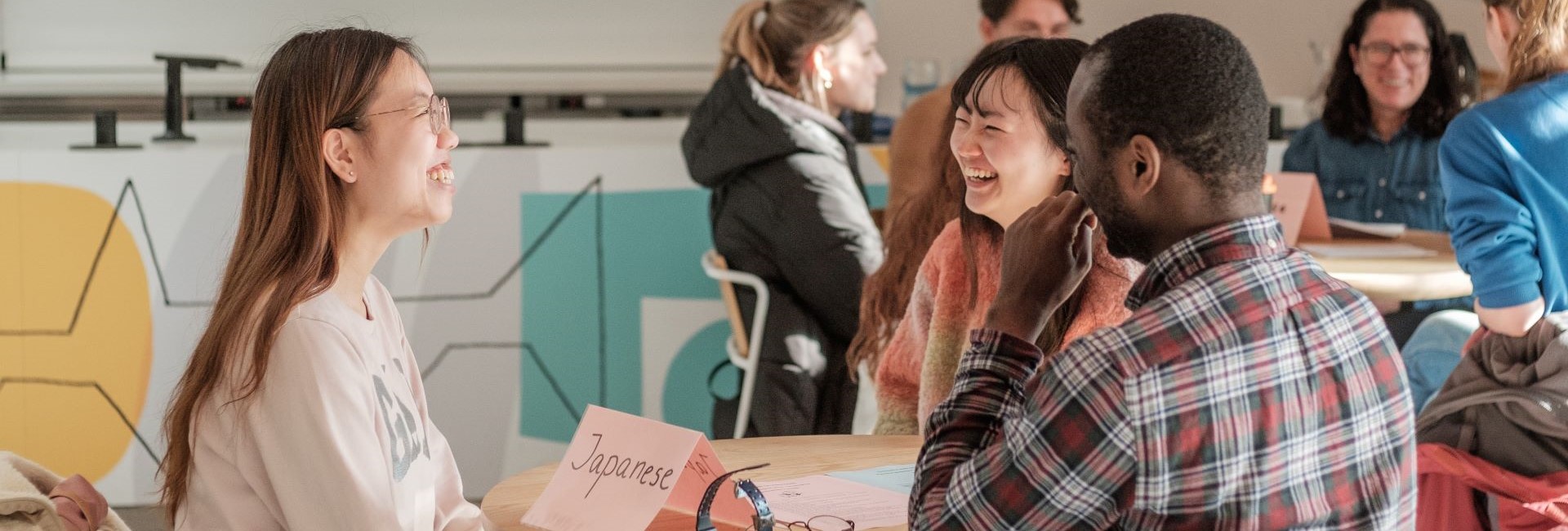 students sat smiling and laughing around a table