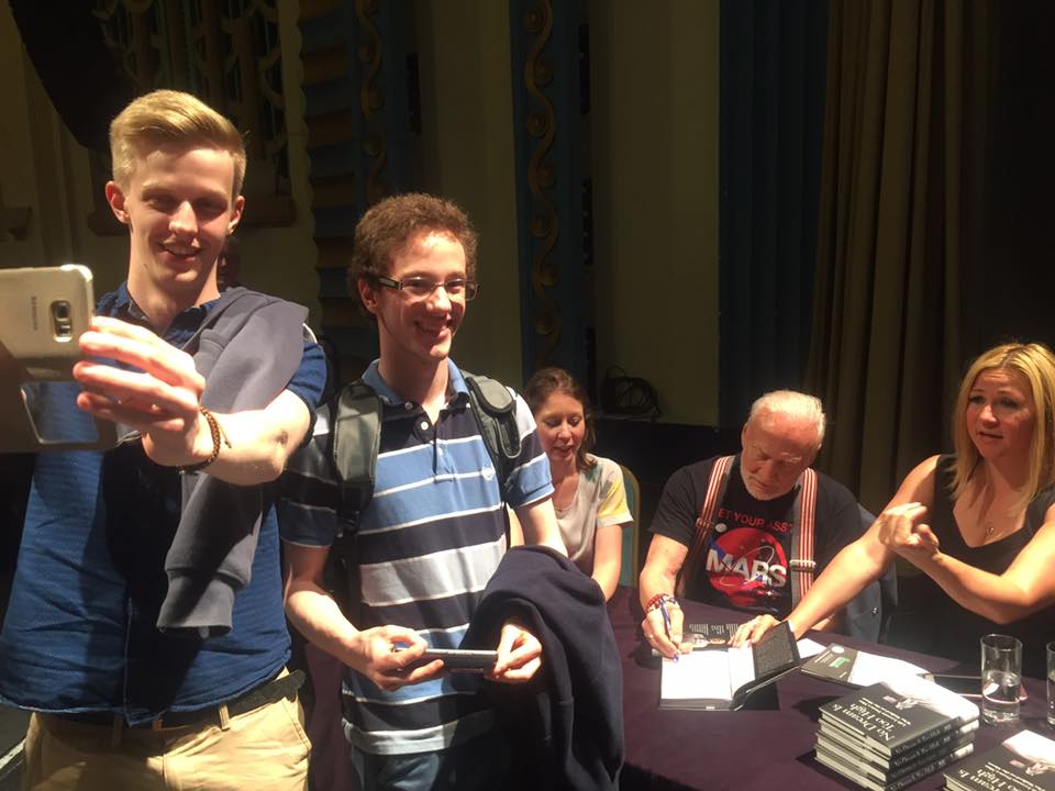 Buzz is signing a book while the two SpaceSoc members smile for the camera.